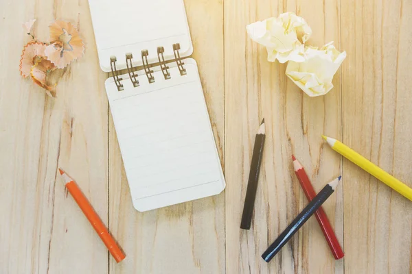 Papier pour carnet de notes (bloc-notes) pour écrire des informations avec crayon de couleur et boules de papier froissées sur une table en bois. vue d'en haut — Photo