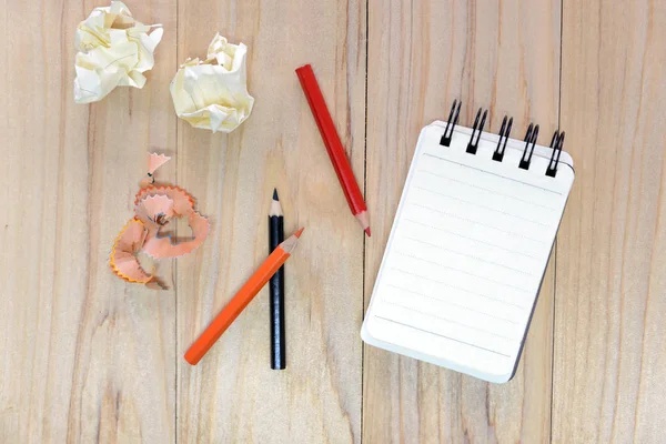Небольшая записная книжка (блокнот) для записи информации цветным карандашом и мятыми бумажными шариками на деревянный стол. вид сверху — стоковое фото
