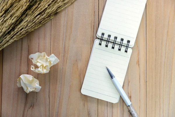 Carta da taccuino (blocco note) per scrivere informazioni con penna, matita a colori e palline di carta spiegazzate su tavolo di legno. vista dall'alto — Foto Stock