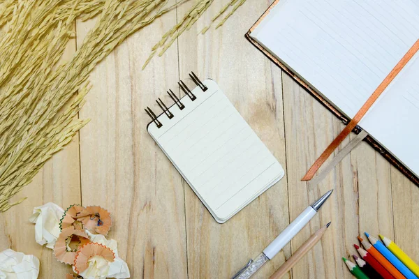 작은 메모도 서 용지 (메모장) 펜, 정보를 작성 하기 위한 컬러 연필, 연필, 책 그리고 구겨진 종이 공을 나무 테이블에. 위에서 보기 — 스톡 사진