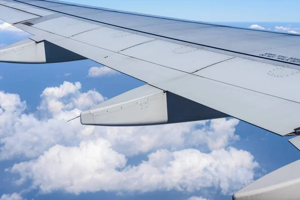 Wing of the plane flying above the clouds. View from the window of an airplane — Stock Photo, Image