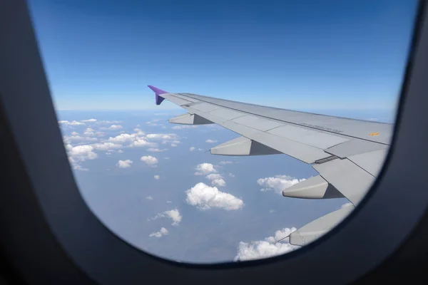 Wing of the plane flying above the clouds. View from the window of an airplane — Stock Photo, Image