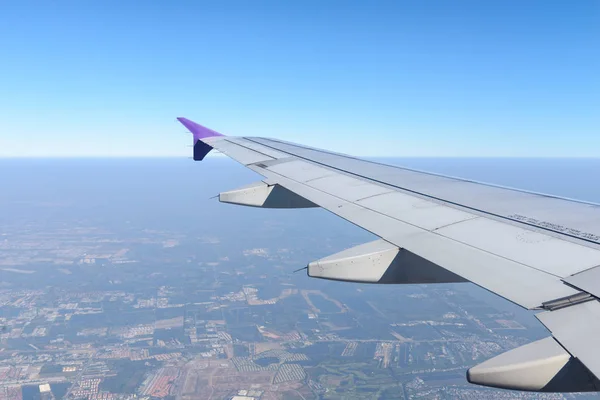 Wing of the plane flying above the city. View from the window of an airplane — Stock Photo, Image