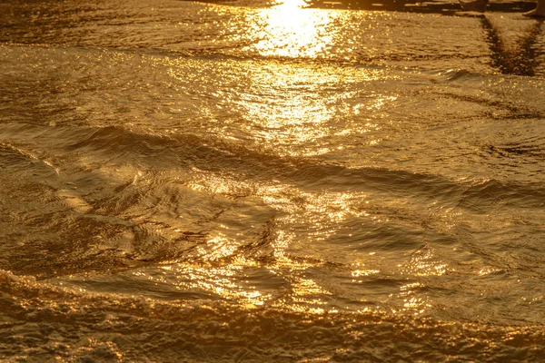 Goldenes Licht, das eine Wasserwelle am Meer und Sand bei Sonnenuntergang reflektiert. reiner Goldton — Stockfoto