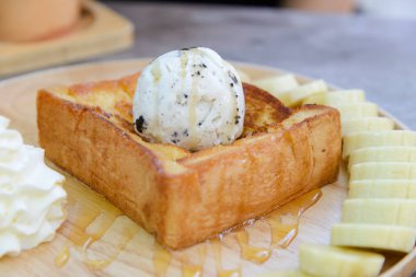 Bal tost. Tatlım yan yemekler çırpılmış krema ve muz ahşap çanak ile tepesinde ekmek arası dondurma