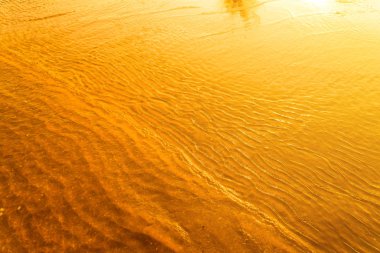 Sunset bulvarında bir su dalga deniz ve kum kapalı yansıtan altın ışık. Saf altın ton