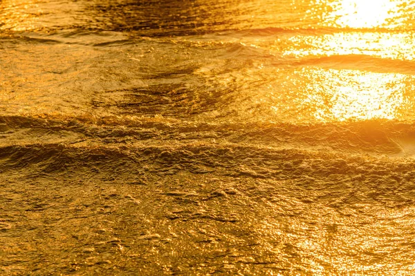 Złote światło odbite od wody fala na morzu i piasku na zachód słońca. Czysty ton złota — Zdjęcie stockowe