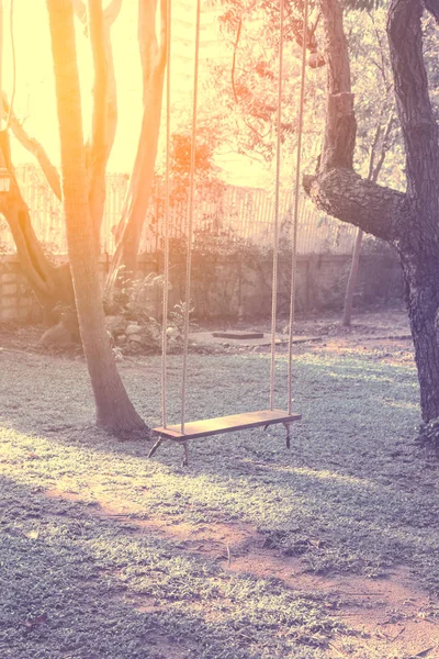 Leere Holzschaukel, die an einem großen Baum mit Sonnenlicht im Garten hängt - Vintage-Farbfilter — Stockfoto