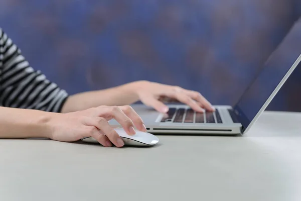 Mujer que trabaja con el ordenador portátil en la mesa, la mano de la mujer usando el teclado portátil y el ratón del ordenador —  Fotos de Stock