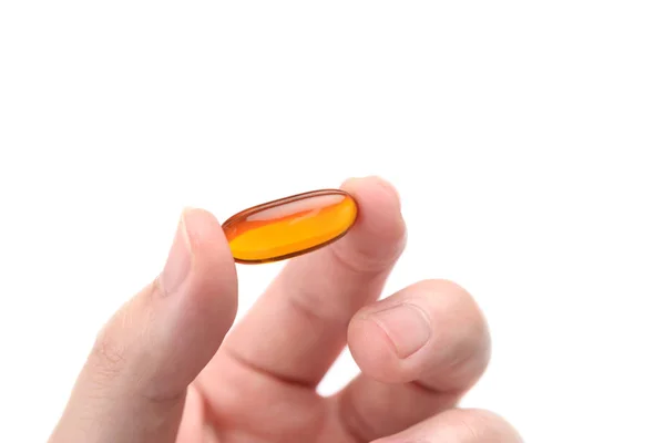 Close up to fish oil capsule in fingers on white background — Stock Photo, Image