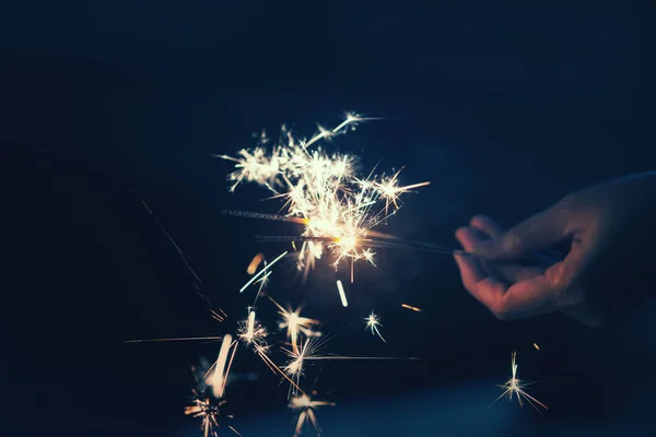 夜背景で線香花火を保持している女性の手 — ストック写真