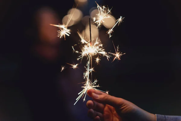 Mãos femininas segurando sparkler com fundo noturno — Fotografia de Stock