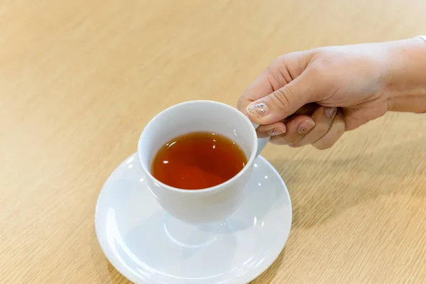 Closeup hand of female holding a cup of hot tea in the meeting room