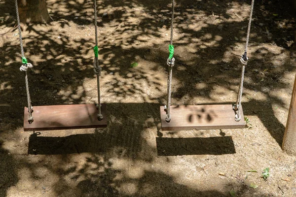 Leere Holzschaukel mit Sonnenlicht auf Spielplatz — Stockfoto