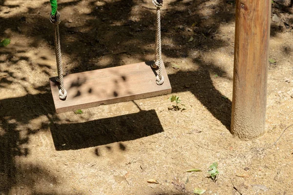 Balanço de madeira vazio com luz solar no parque infantil — Fotografia de Stock