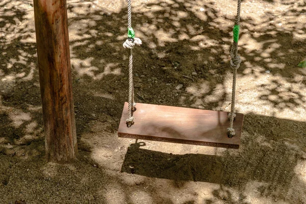 Balanço de madeira vazio com luz solar no parque infantil — Fotografia de Stock