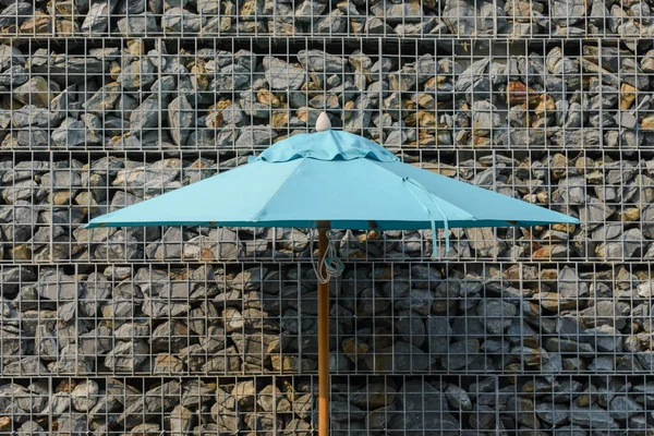 Częścią duży parasol z gabionowe skalnej ściany na tle z bliska — Zdjęcie stockowe