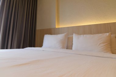 yatağa yastık istifleme, ahşap yatak başı ile beyaz yatak çarşafları