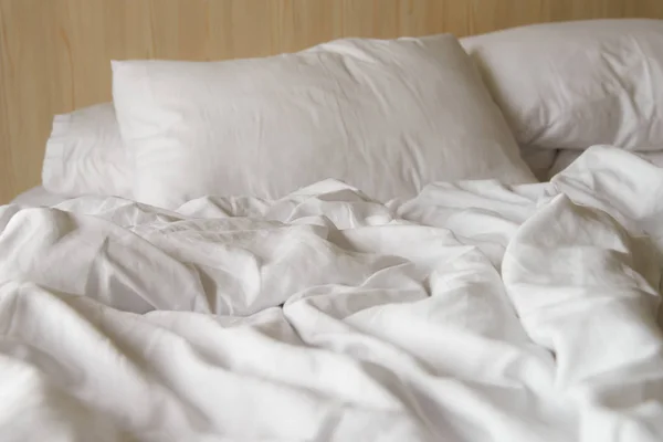 Gerimpelde witte deken met zachte kussens op comfortabel bed in de ochtend. verknoeid na nachtrust — Stockfoto