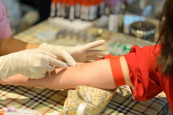 Закрыть медсестру уколоть иглой шприц к вене пациента, беря образец крови для анализа крови — стоковое фото