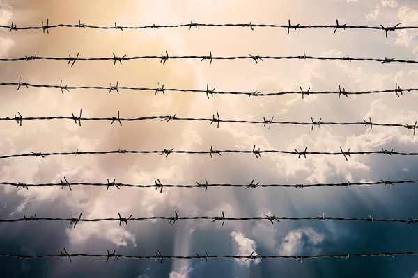 Cerca de alambre de púas con cielo nublado y luz de rayos. Siéntete silencioso y solo y quiere libertad — Foto de Stock