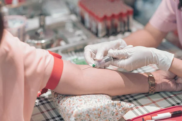 Закрыть медсестру уколоть иглой шприц к вене пациента, беря образец крови для анализа крови — стоковое фото