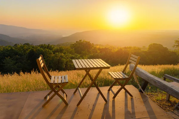 Lege houten tafel en stoelen op terras. Mooi zitje met uitzicht op de bergen tijdens zonsondergang. — Stockfoto