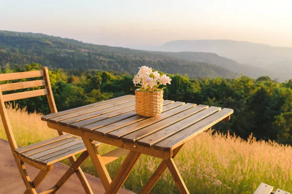 Bloempot op houten tafel en stoelen op terras. Mooi zitje met uitzicht op de bergen tijdens zonsondergang. — Stockfoto