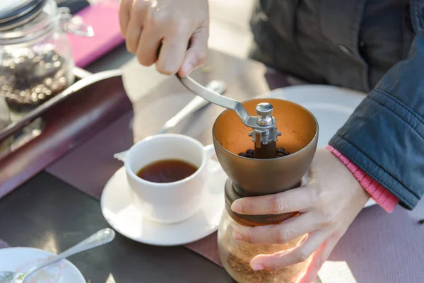 Mujeres asiáticas manos en el café molinillo manual para moler granos de café en la mesa con fondo verde natural sensación de frío y relajarse en la naturaleza — Foto de Stock