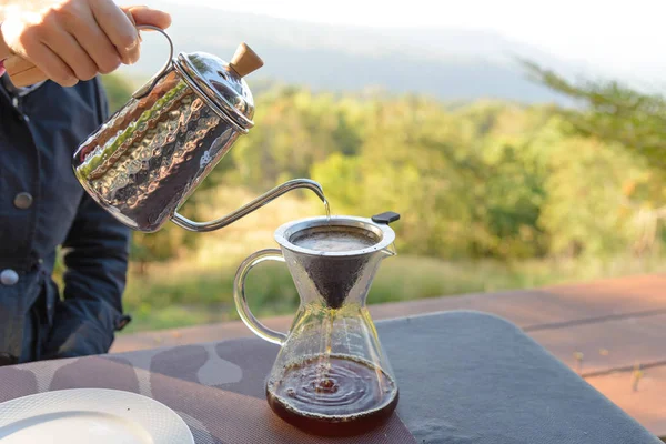 Mano de café goteo hacer verter sobre el café con agua caliente que se vierte desde una tetera con vista a la montaña y verde natural sensación de frío y relajarse en la naturaleza — Foto de Stock