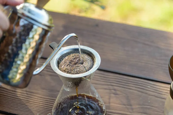 Hand drip coffee making pour over coffee with hot water being poured from a kettle with mountain view and natural green view feeling chill and relax in nature