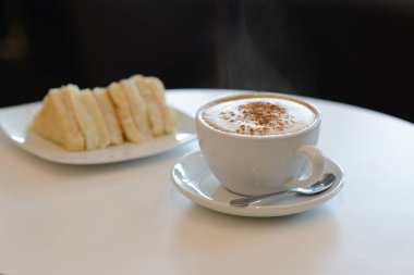 Sabahları kahvaltıda bir fincan sıcak kapuçino ve sandviç.