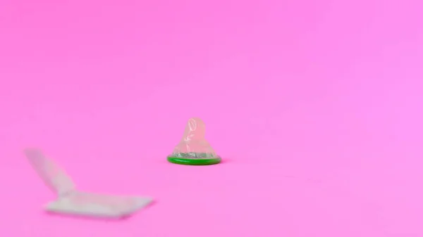 Grünes Kondom auf rosa Papierhintergrund mit Kopierraum für Text. reproduktive Gesundheit und Safe Sex Konzept — Stockfoto