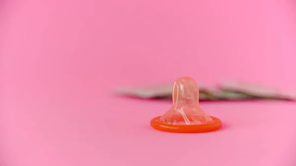 ピンクの紙の背景にコンドムパックで赤いコンドームを開きました 生殖の健康 安全なセックスの概念 — ストック写真