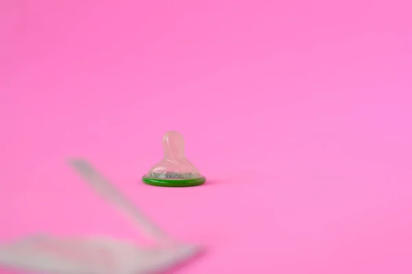 テキストのコピースペースとピンクの紙の背景に緑のコンドーム 生殖の健康と安全なセックスの概念 — ストック写真