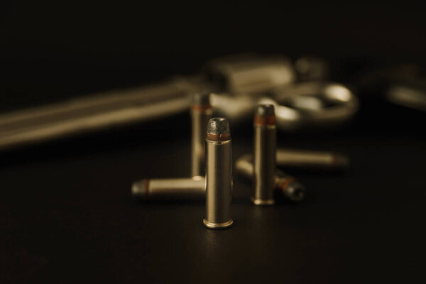 357 Caliber hollow point bullets near revolver pistol gun on black background