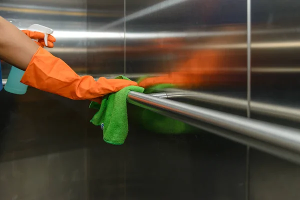 緑のマイクロファイバークリーニング布を保持し スプレー滅菌ソリューションを使用してほこりを拭く保護オレンジゴム手袋の女性の手は良い衛生のためのクリーニングと消毒を行います — ストック写真