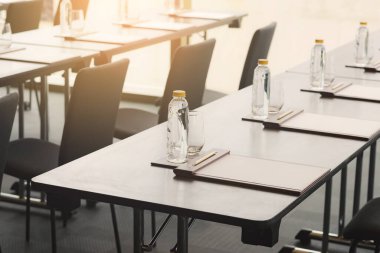 Plastik su şişeleri, kalem ve beyaz kağıtlı içki bardakları otel konferans odasında seminer ya da iş toplantısı için hazırlandı.