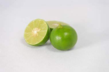 Taze yeşil limonlar, beyaz branda arka planda dilimlenmiş.