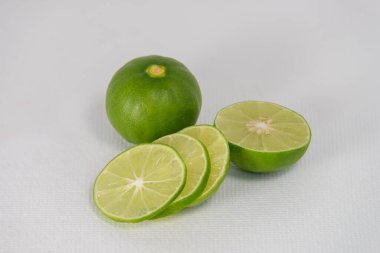 Taze yeşil limonlar, beyaz branda arka planda dilimlenmiş.