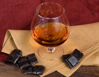 Bardak brendi ve ahşap masa çikolata