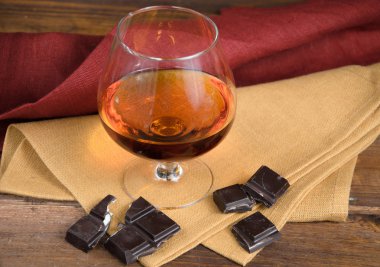 Bardak brendi ve ahşap masa çikolata