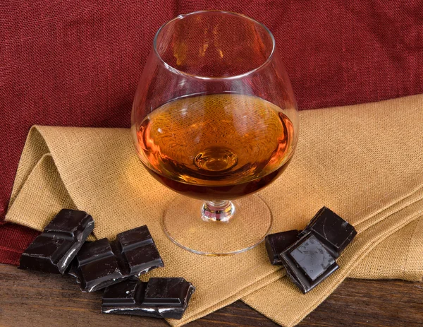 Bardak brendi ve ahşap masa çikolata