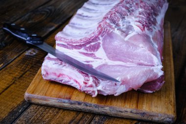 Tahta arka planda pirzola ve taze çiğ domuz filetosu.