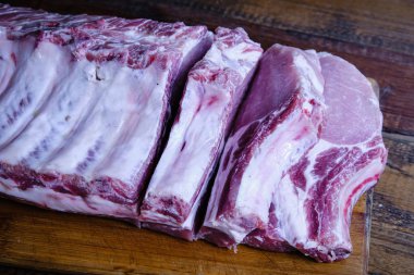 Tahta arka planda pirzola ve taze çiğ domuz filetosu.