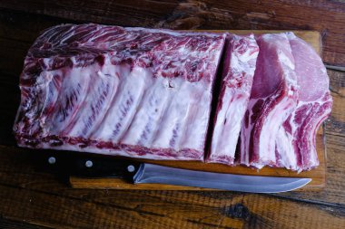 Tahta arka planda pirzola ve taze çiğ domuz filetosu.