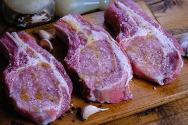 Tahta arka planda pirzola ve taze çiğ domuz filetosu.