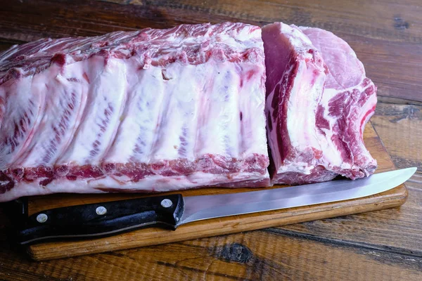 Tahta arka planda pirzola ve taze çiğ domuz filetosu.