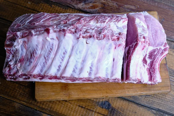 Tahta arka planda pirzola ve taze çiğ domuz filetosu.