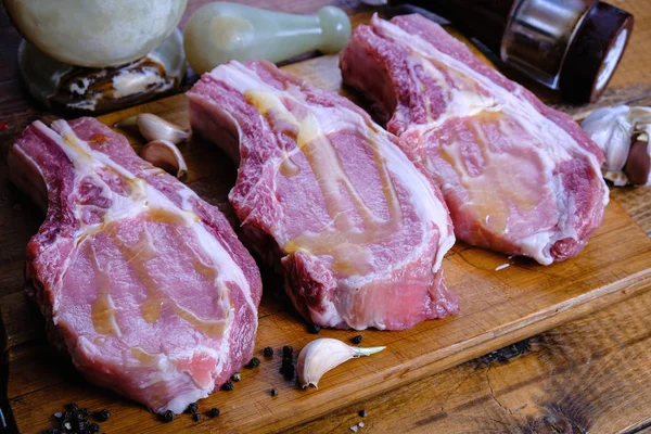 Tahta arka planda pirzola ve taze çiğ domuz filetosu.